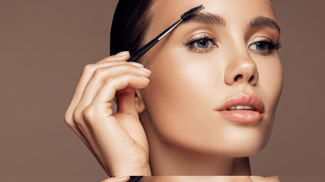 A woman brushing her eyebrows with a spoolie