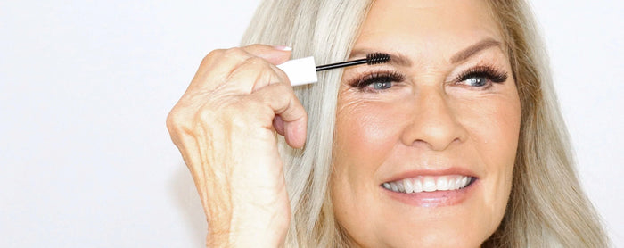 Lady with grey hair brushing her brows up