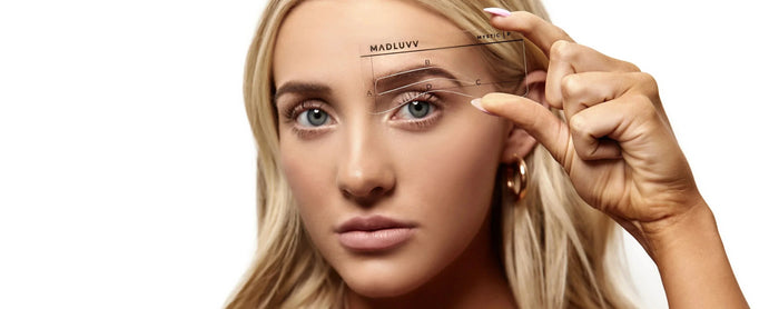 Woman holding stencil to eyebrow