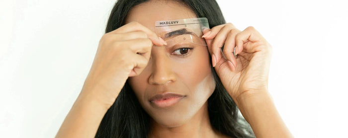 A woman holding a brow stencil