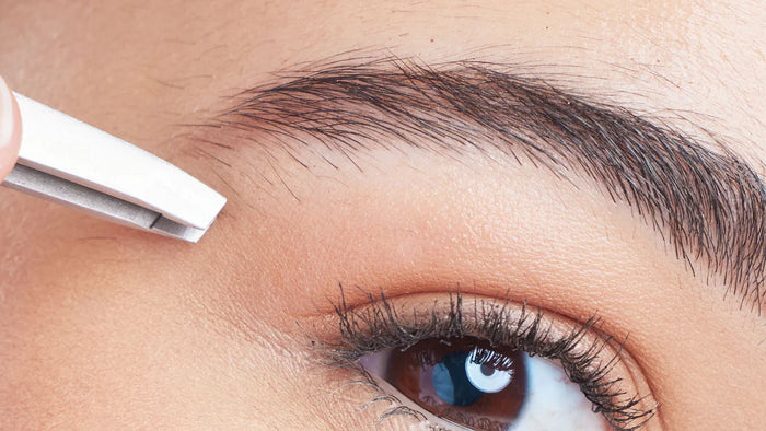 Woman tweezing eyebrow hairs