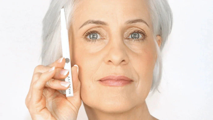 grey haired woman holding a brow pencil